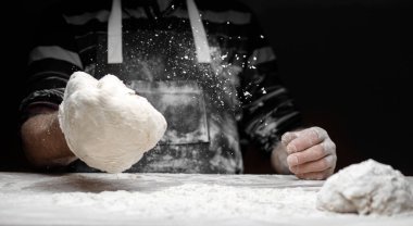 Erkek fırıncının elleri siyah arka planda beyaz un tozuyla maya hamur mayası hazırlıyor, makarna ve pizza için kepçeyle.