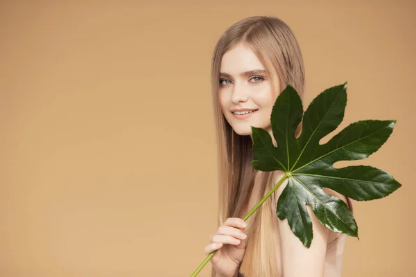 Retrato joven hermosa mujer con la piel lisa en hojas tropicales en el estudio. Concepto cuidado de la piel cosmética flora natural —  Fotos de Stock