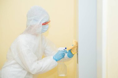 Coronavirüs dezenfeksiyonu. Tehlikeli maddeler kullanan insanlar asansör dairesinde temizlik yapıyorlar.