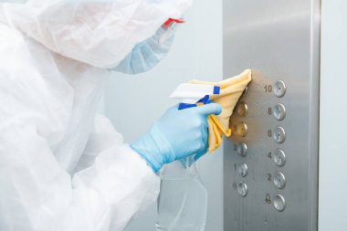 Coronavirüs dezenfeksiyonu. Tehlikeli maddeler kullanan insanlar asansör dairesinde temizlik yapıyorlar.