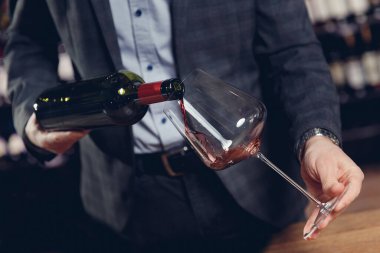 Sommelier adam bardağa su sıçratmadan kırmızı şarap doldurur.