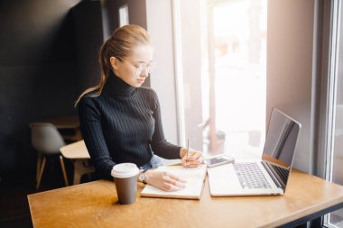 Yakın plan kadın eli not ve defter tutuyor, öğrenci kadın evde otururken çalışıyor ve çalışıyor.