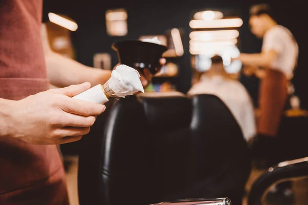 Close-up razor in hands of barber, background client is waiting for shaving beard and mustache — Stock Photo, Image