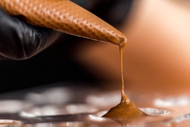 Şef ya da çikolatacı eritilmiş siyah çikolatayı pasta poşetinin üzerine silikon kalıplara döküyor.