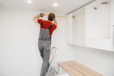 Mobilya dolabı menteşesi monte eden bir işçi. Mutfak tamircisi.