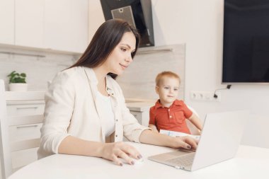 Doğum izninde olan bir kadın evde dizüstü bilgisayarla küçük bir çocukla birlikte çalışıyor. Anne kavramı, Covid-19 sırasında karantina izolasyonundayken çalışıyor.