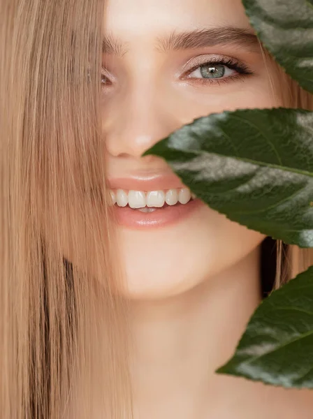 Concept soins buccodentaires dents et gommes.Portrait femme avec feuille verte naturelle, fille modèle blonde avec sourire — Photo