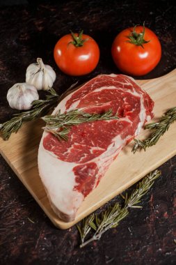Biberiye, sarımsak ve domates bir delikanlı ile süslenmiş ham antrikot biftek