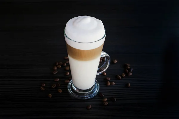 Cappuccino café e espuma de leite em uma xícara transparente no fundo preto — Fotografia de Stock