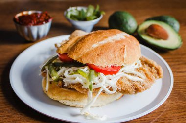 Mexican torta is chicken milanese sandwich with avocado, chili chipotle and oaxaca cheese clipart