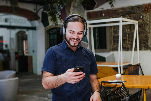 Mexican Man in headphones listening music with his smartphone in Mexico city