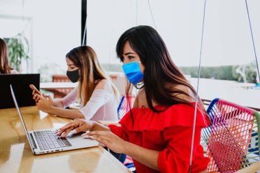 İş yerinde çalışan Latin bir kadın sosyal mesafeyi korumak için yüz maskesi takıyor Corona virüsü veya Meksika 'daki Cvid-19 Meksikalı insanların enfeksiyonunu önlüyor.