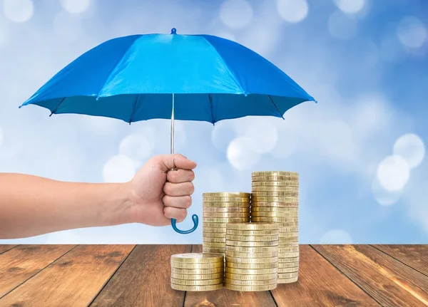 Монеты под синим зонтиком — стоковое фото