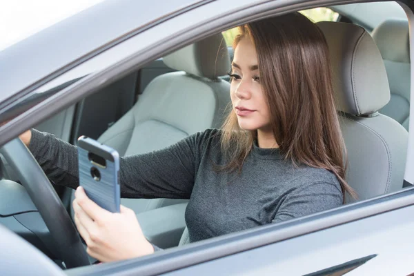 Adolescente chica conducir coche mientras mensajes de texto —  Fotos de Stock