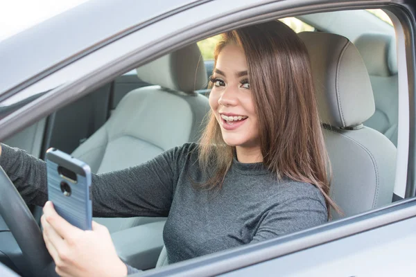 Adolescente menina dirigindo carro enquanto mensagens — Fotografia de Stock