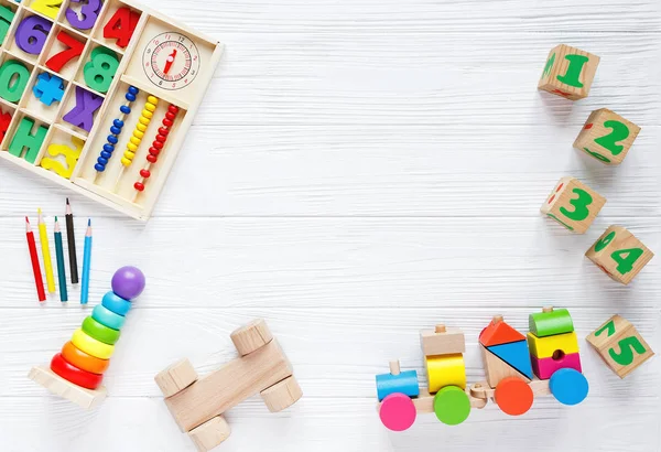 Kids toys: pyramid, wooden blocks, xylophone, train on white wooden background. Top view. Flat lay. Copy space for text