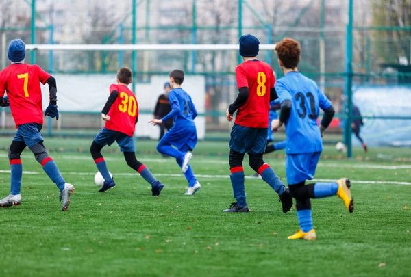 Chłopcy Czerwonym Niebieskim Stroju Sportowym Grają Piłkę Boisku Dryblują Młodzi — Zdjęcie stockowe