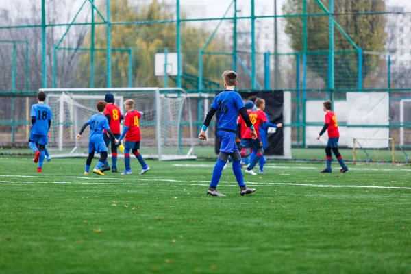 赤と青のスポーツウェアの少年たちは フィールドにサッカー ドリブルボールを果たしている 緑の芝生の上でボールを持つ若いサッカー選手 トレーニング サッカー 子供のためのアクティブなライフスタイルの概念 — ストック写真