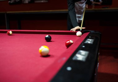 Boy plays billiard or pool in club. Young Kid learns to play snooker. Boy with billiard cue strikes the ball on table. Active Leisure, sport, hobby concept