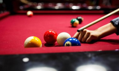 Boy plays billiard or pool in club. Young Kid learns to play snooker. Boy with billiard cue strikes the ball on table. Active Leisure, sport, hobby concept