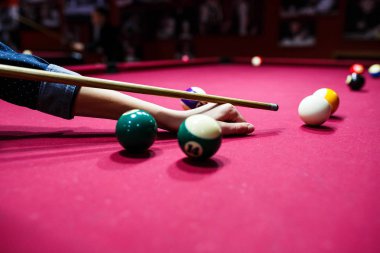 Boy plays billiard or pool in club. Young Kid learns to play snooker. Boy with billiard cue strikes the ball on table. Active Leisure, sport, hobby concept