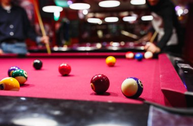 Boy plays billiard or pool in club. Young Kid learns to play snooker. Boy with billiard cue strikes the ball on table. Active Leisure, sport, hobby concept