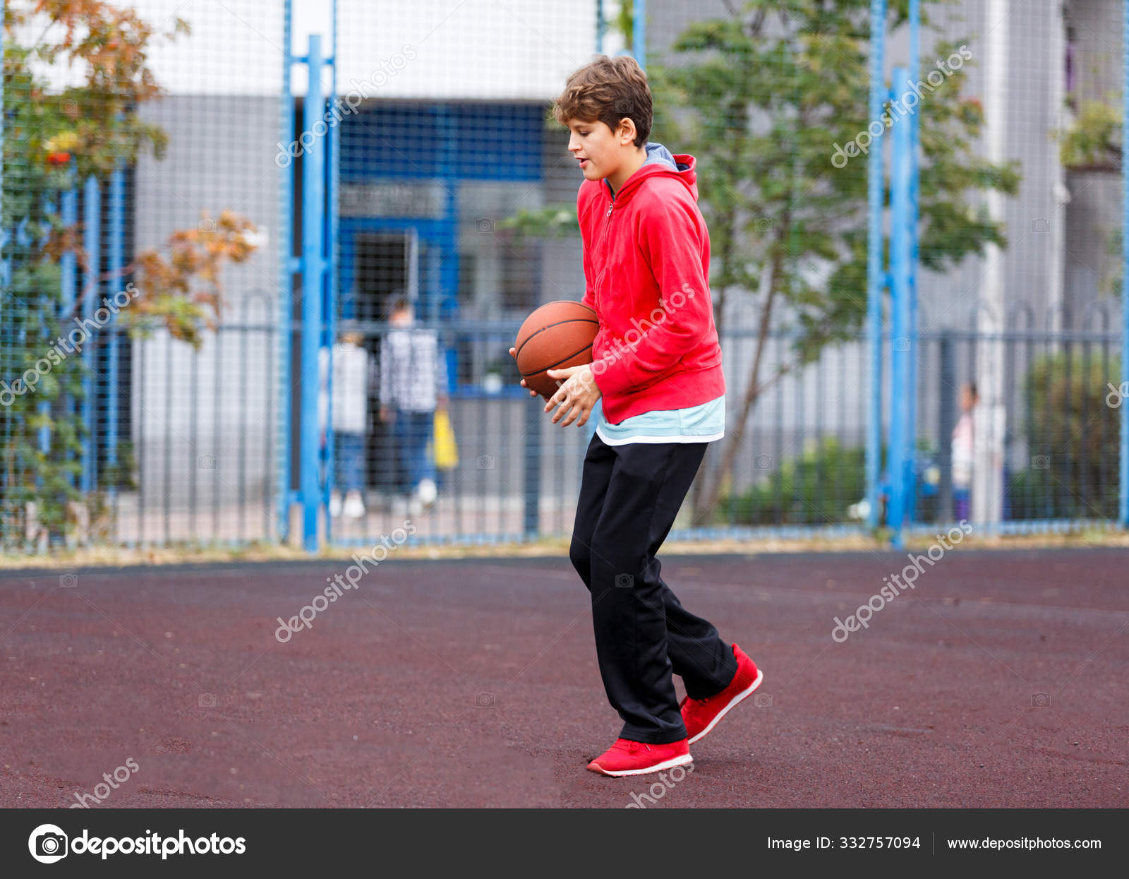 Jovem jogador de basquete feliz sentado no parque com uma toalha