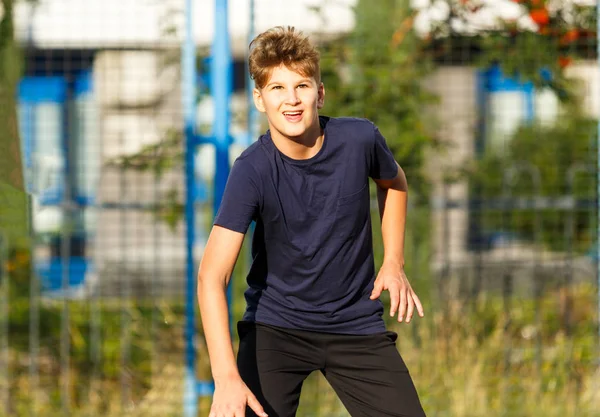 Boy in a sports suit playing basketball outside
