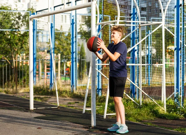 Boy in a sports suit playing basketball outside