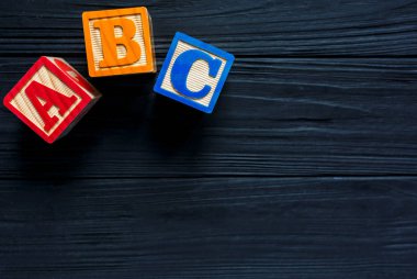 Ahşap çocuklar koyu tahta arka planda blok yapıyorlar. Eğitici oyuncaklar blokları. Anaokulu, anaokulu ya da kreş için oyuncaklar. Uzayı metin için kopyala. Üst görünüm, modelle