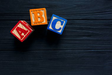 Ahşap çocuklar koyu tahta arka planda blok yapıyorlar. Eğitici oyuncaklar blokları. Anaokulu, anaokulu ya da kreş için oyuncaklar. Uzayı metin için kopyala. Üst görünüm, modelle