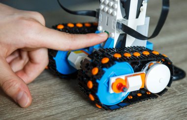 Kyiv, Ukrayna - 02, 09, 2020: Robot Lego Boost Vernie çocuğun ellerinde. Beyaz tişörtlü çocuk evde robot programlıyor. Öğrenci çocuk öğreniyor ve robotla oynuyor. Kök eğitim. Kapat.