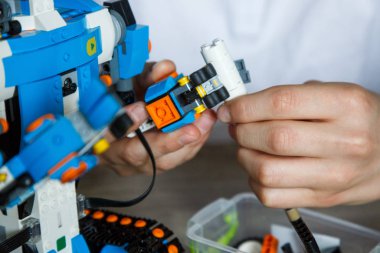 Kyiv, Ukrayna - 02, 09, 2020: Robot Lego Boost Vernie çocuğun ellerinde. Beyaz tişörtlü çocuk evde robot programlıyor. Öğrenci çocuk öğreniyor ve robotla oynuyor. Kök eğitim. Kapat.