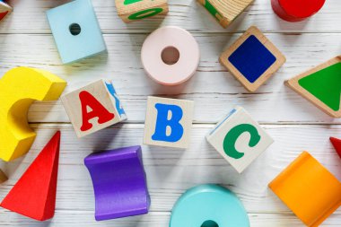 Çocuk oyuncakları: piramit, tahta bloklar, beyaz ahşap arka planda tren iskeleti. Eğitim, anaokulu oyunları. Üst Manzara. Düz yatıyordu.