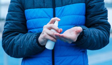 Çocukların elleri şehrin sokaklarında el yıkamak için dezenfektan kullanıyor. Çocuk, Corona virüsü salgınında ellerini korumak için alkol spreyli şişe kullanıyor. 