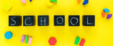 Sarı arka planda renkli matematik kesirleri. Masada unvan okulu olan bloklar. Çocuklar için ilginç, eğlenceli matematik. Eğitim, okula dönüş konsepti.