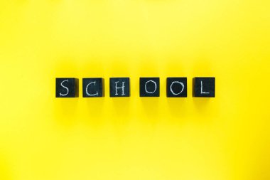 Sarı arka planda unvan okulu olan bloklar. Eğitim, okula dönüş konsepti..