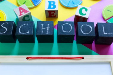 Yeşil, sarı ve mor arkaplanda renkli matematik kesirleri var. Masada unvan okulu olan bloklar. Çocuklar için ilginç, eğlenceli matematik. Eğitim, okula dönüş konsepti.