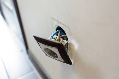 Duvardan kahverengi kırık elektrik prizi düştü. Priz duvardan sökülmüş. Elektrik güvenliği ihlali, elektrik şoku riski