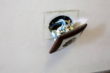 Duvardan kahverengi kırık elektrik prizi düştü. Priz duvardan sökülmüş. Elektrik güvenliği ihlali, elektrik şoku riski.