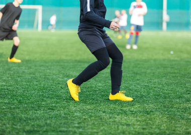 Futbol sahasında koşan beyaz takım elbiseli çocuklar. Genç futbolcular maçta top sürüp tekmeliyorlar. Eğitim, aktif yaşam tarzı, spor, çocuk aktivitesi konsepti