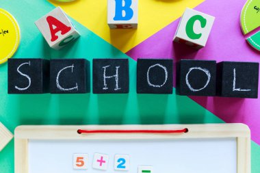 Yeşil, sarı ve mor arkaplanda renkli matematik kesirleri var. Masada unvan okulu olan bloklar. Çocuklar için ilginç, eğlenceli matematik. Eğitim, okula dönüş konsepti.