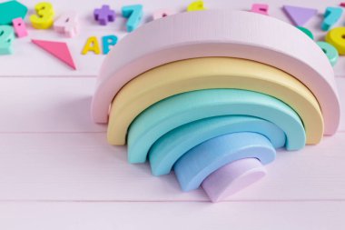Tahta oyuncak gökkuşağı, pembe arka planda pastel renk yayı. Yaratıcılık gelişimi için plastik oyuncaklar yok. Anaokulu, anaokulu çocukları için eğitici oyunlar
