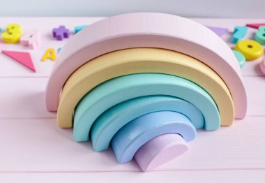 Tahta oyuncak gökkuşağı, açık pembe arka planda pastel renk yayı. Yaratıcılık gelişimi için plastik oyuncaklar yok. Düz yerde, üst tarafta. Anaokulu, anaokulu çocukları için eğitici oyunlar