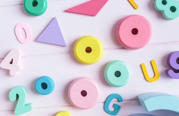 Wooden toy rainbow, numbers, blocks, pastel color arc on pink background. Natural no plastic toys for creativity development. Flat lay, top view. Educational games for kindergarten, preschool kids