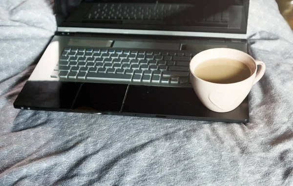 Close up of laptop and cup of coffee in the bed. Workspace for freelance, lifestyle. Distance work, online working, freelance concept.