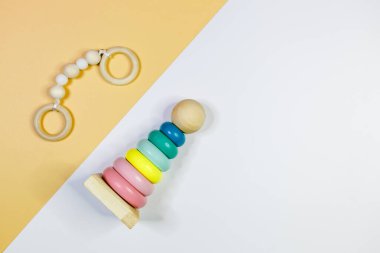 Sarı arka planda farklı şekillere sahip şirin, küçük tahta bebek bağcıklarını kapatın. Yeni doğan bebekler için eko aksesuarlar, bebeğim. Düz yatış, üst görünüm