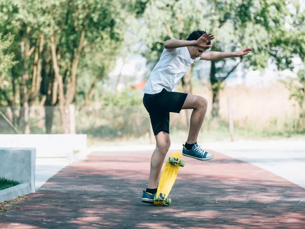 身穿白色T恤的青少年在公园里花时间训练滑冰 可爱的好孩子喜欢在户外玩滑板 Hobby 儿童体育 — 图库照片