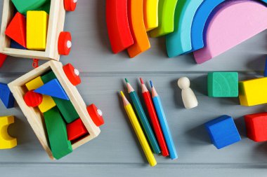 Çok renkli tahta küpleri harflerle, kalemlerle, gri arka planda gökkuşağı kavisleriyle kapatın. Alfabe çalışmak için oyuncak seti. Eğitim, okul konseptine geri dönelim. Üst görünüm, alanı kopyala