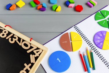 Gri ahşap masadaki açık not defterindeki çok renkli matematik kesirlerini kapat. Çocuklar için ilginç bir matematik. Eğitim, okula dönüş konsepti.